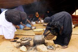 Image du Maroc Professionnelle de  Sous une tente bédouine plusieurs femmes du Sahara  préparent le couscous durant le grand Moussem de Tan Tan, classé en 2005 patrimoine immatériel humain mondial de l'Unesco. Le Moussem est une sorte de foire annuelle, à la fois économique, culturelle et sociale. Chaque année la majorité des tribus et des grandes familles nomades du désert se retrouvent sur un site désertique "Place de la Tolérance et de la Paix " à la périphérie de Tan Tan où  danse, chants, course de chameaux et fantasia font partie des festivités. , Samedi 18 septembre 2004, ((Photo / Abdeljalil Bounhar) 